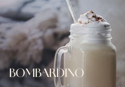 Glas mit ECKES Bombardino, garniert mit Sahne und Schokoladenstreuseln, vor einem gemütlichen Hintergrund