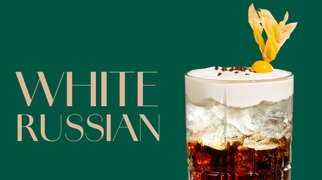 Glas mit White Russian Cocktail, gekrönt von einer Sahneschicht und einer Zitronenzeste.