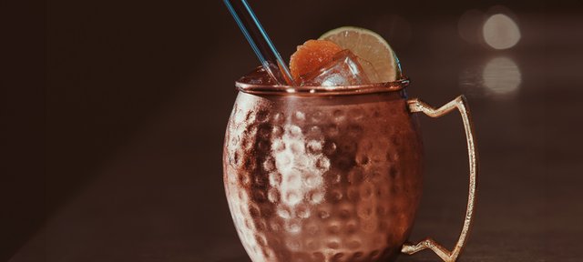 Kupferbecher mit ECKES New Orleans Mule Cocktail auf Eis, garniert mit Limetten- und Orangenscheibe