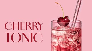 Glas mit ECKES Cherry Tonic Cocktail, garniert mit einer Kirsche und einem Strohhalm, vor einem rosafarbenen Hintergrund