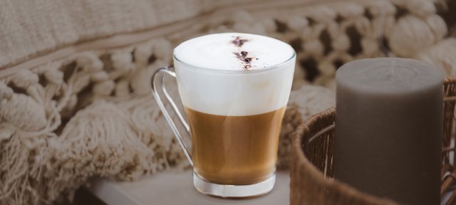 Glas mit ECKES White Russian Cocktail, garniert mit Sahne und Kaffeebohnen, auf einem Tisch vor einem gemütlichen Hintergrund.