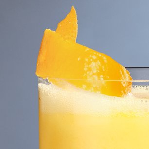  Nahaufnahme eines Eierlikör-Drinks in einem Glas mit Orangenschale als Garnitur.