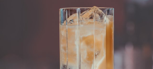 Glas mit ECKES Snowball Cocktail auf Eis, garniert mit einer Zitronenzeste