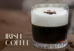 Tumbler-Glas mit irischem Kaffee, gekrönt von einer dicken Schaumkrone und drei Kaffeebohnen.